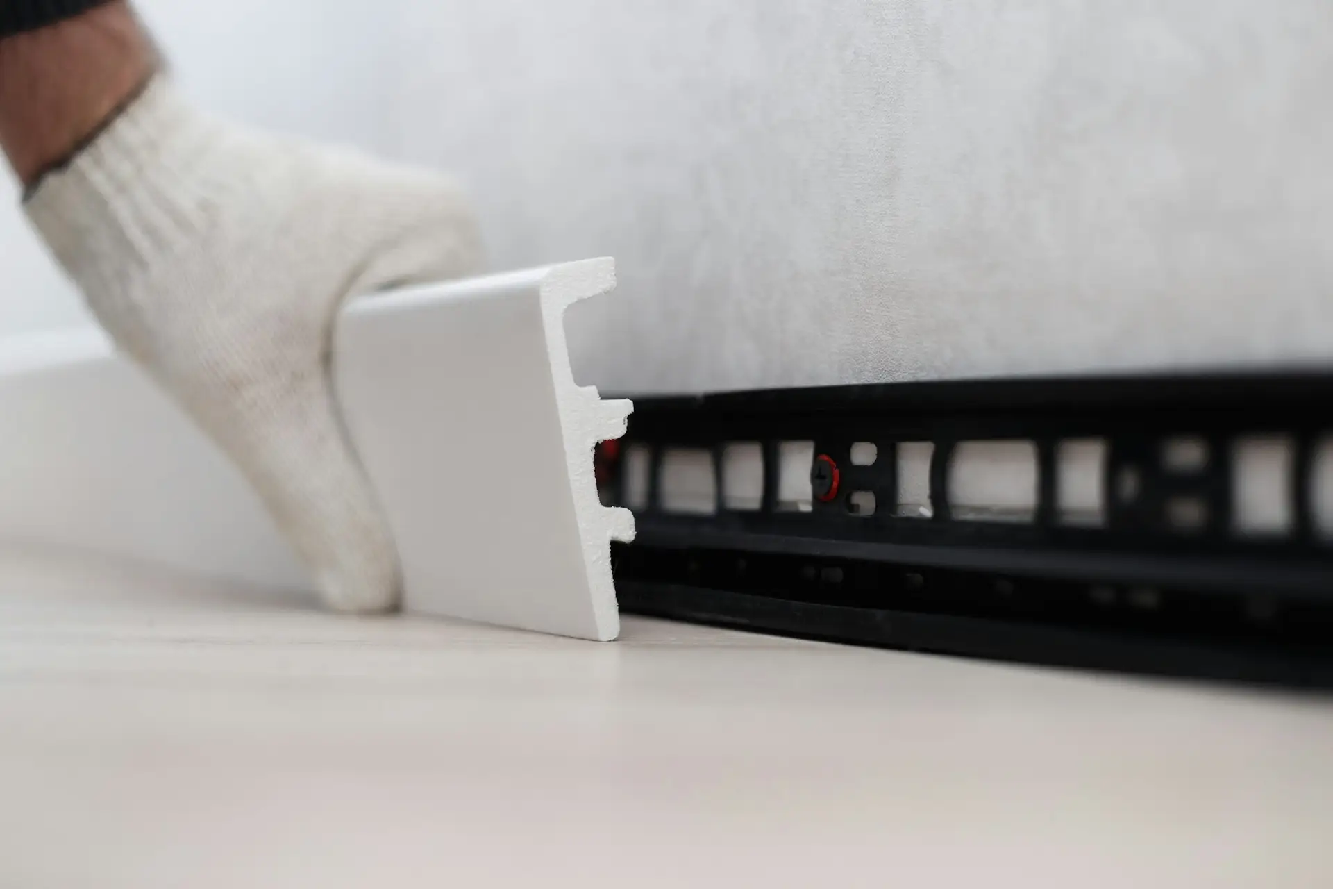 Man putting new skirting board on wall in house