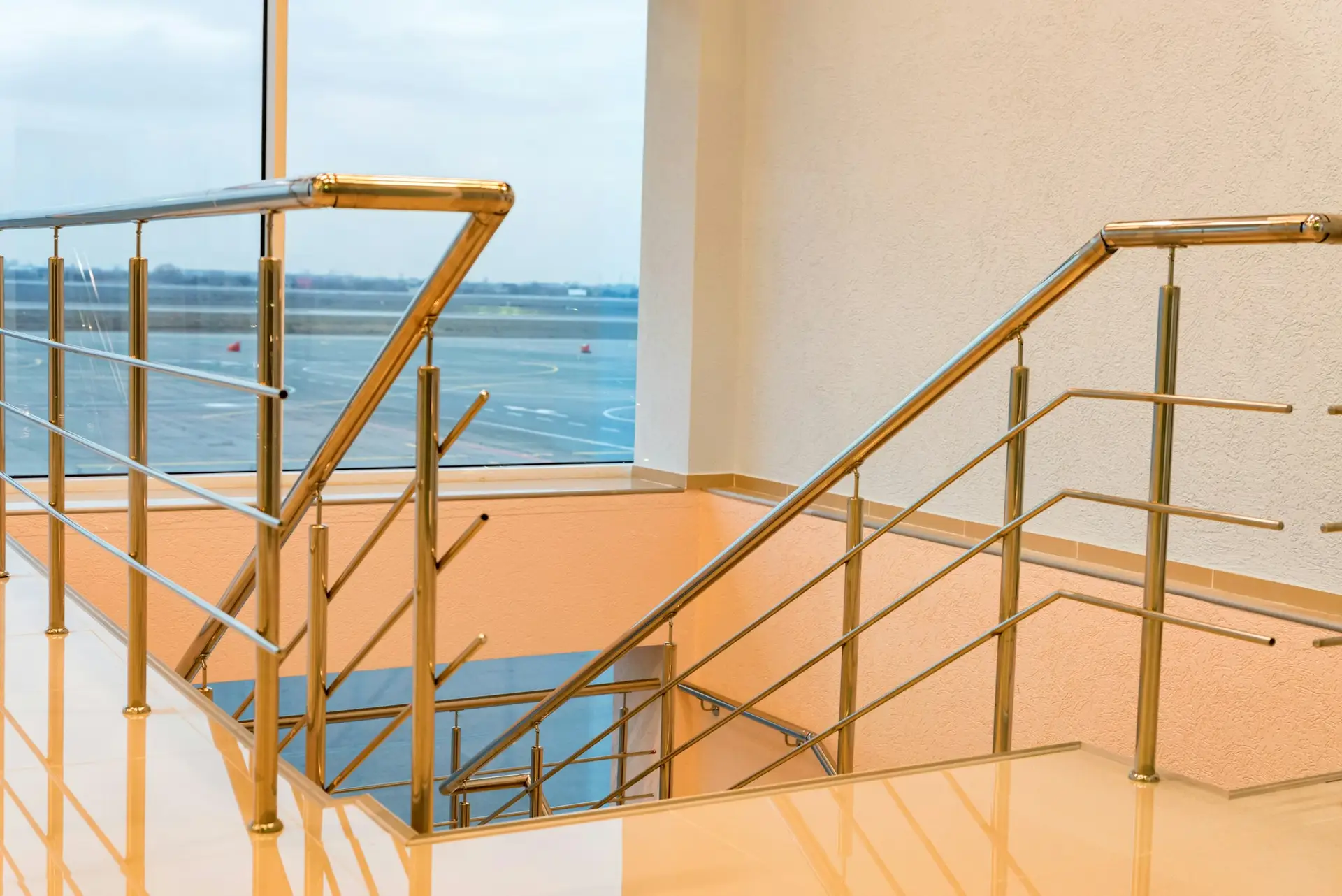 Modern beige airport staircase with the chrome handrails